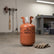 Orange refrigerant tank labeled R407C on a concrete floor with gloves nearby.