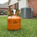 Orange refrigerant canister on grass with air conditioning unit in the background