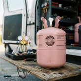 Pink refrigerant canister on a wooden pallet with a vehicle in the background