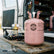 Pink refrigerant canister on a wooden pallet with a vehicle in the background